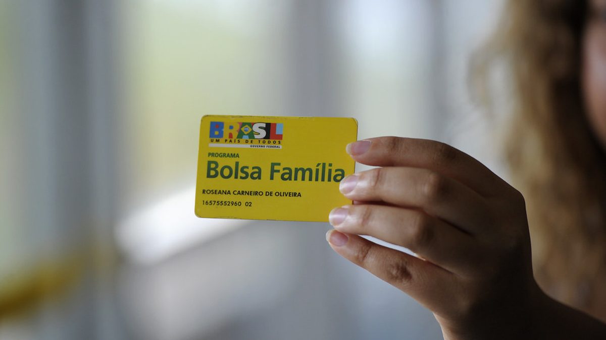 Mão segura o cartão do Bolsa Família