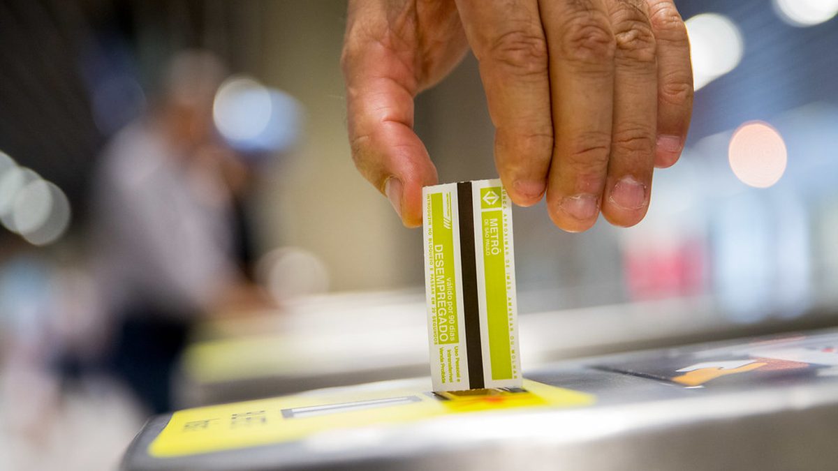 Mão insere bilhete de papel com tarja magnética em catraca do Metrô de São Paulo