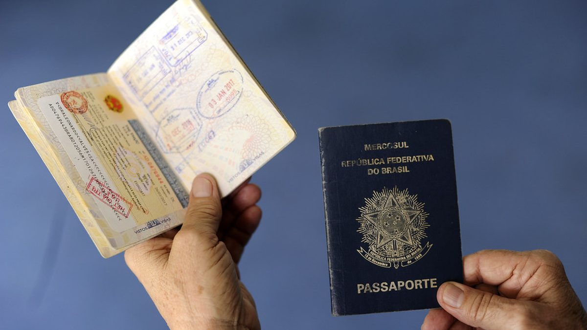 Passaporte brasileiro aberto, com vistos, ao lado de outro fechado