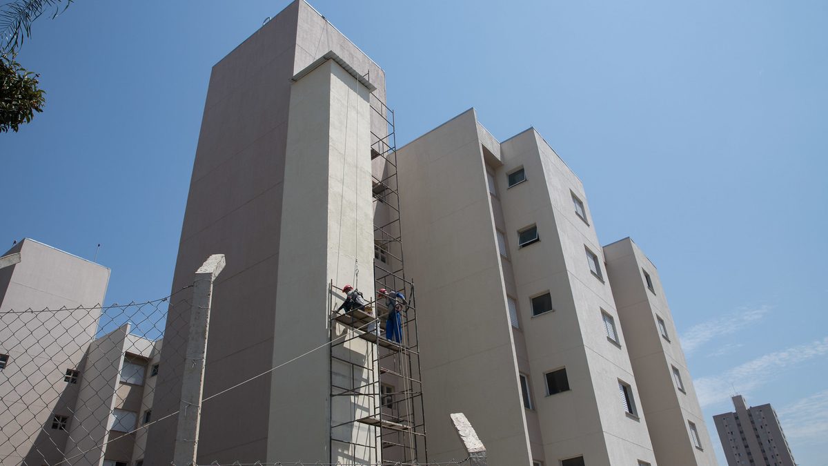 Operários em andaime na fachada de prédios residenciais em obra no estado de São Paulo